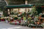 A vibrant outdoor flower market with various colorful blooms in pots and planters.
